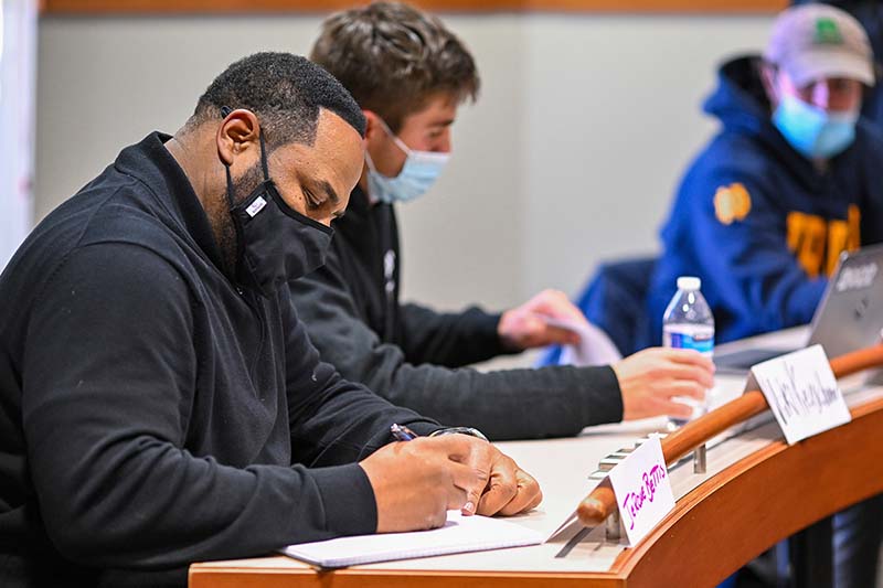 Bettis sits at a desk with other students in a classroom, working.