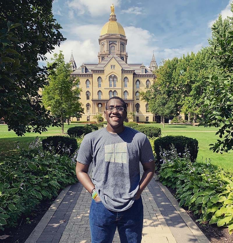 Brown stands in front of Main Building on a sunny day.