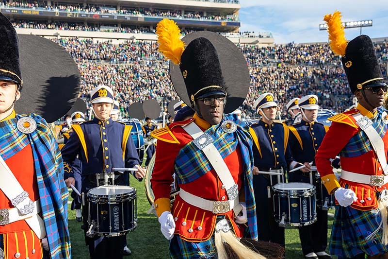 Brown marches with other Irish Guard members on the field of Notre Dame Stadium during football game.