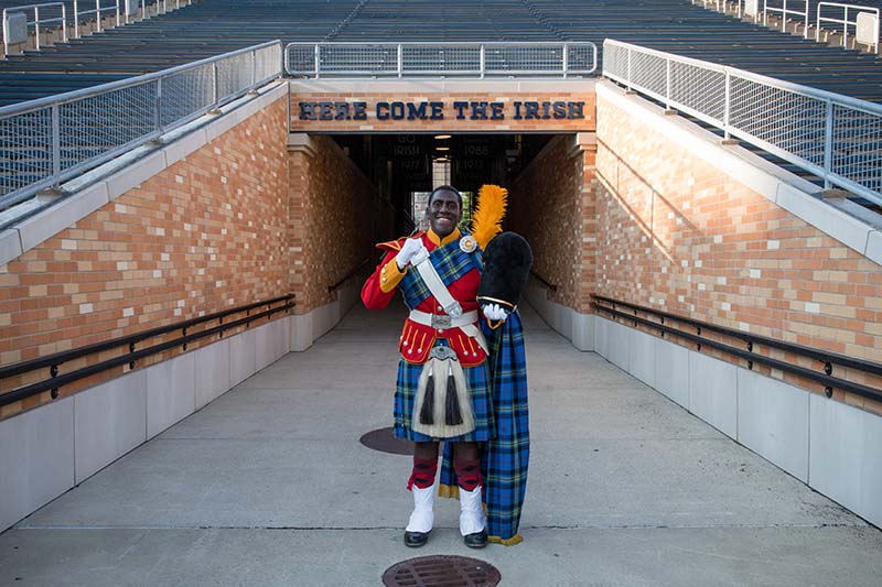 Brown stands in front of the Here Come The Irish tunnel in Notre Dame Stadium wearing his Irish Guard uniform.