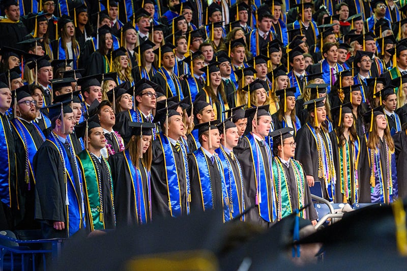 Students standing for mass during ceremony.