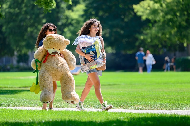 A mother and daughter carrying items on moving in day.