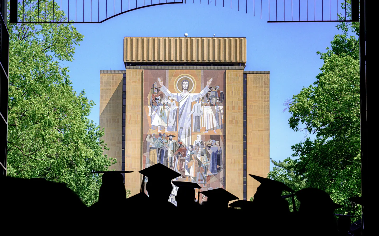 Graduates process from the Stadium entrance towards the Word of Life mural on the Hesburgh Library. 