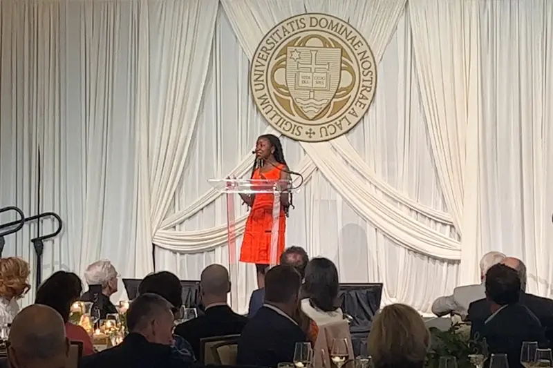 Agwu stands at a podium wearing a red dress.