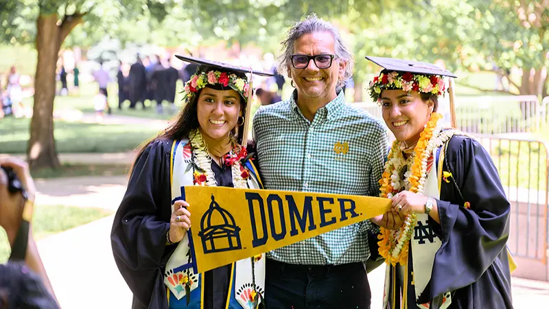 Students posing with loved ones after commencement ceremonies.