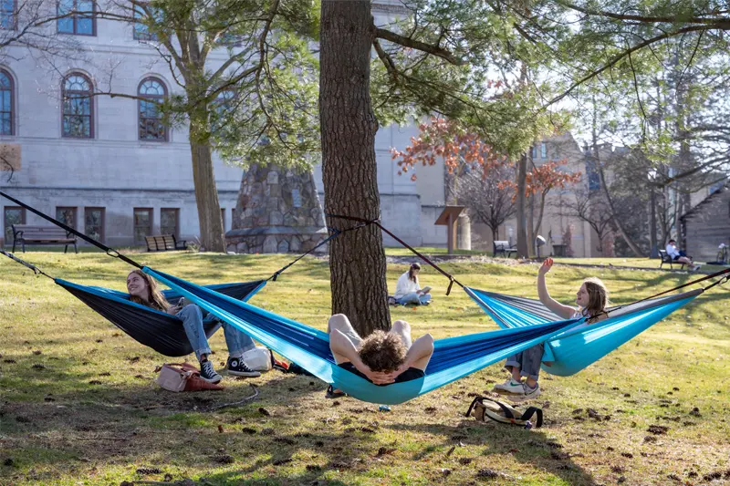 Three students hanging in hammocks outside bond hall.