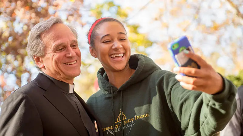 Rev. John I. Jenkins, C.S.C. takes a selfi with an undergrad on campus.