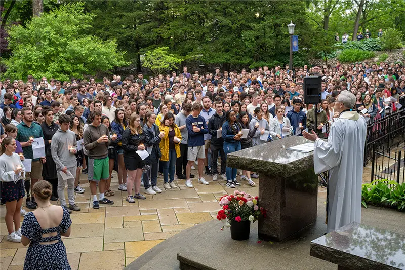 A crowd of graduating seniors gather around the grotto as Rev. John I. Jenkins, C.S.C. leads the prayer service at the Senior Last Visit to the Grotto during Senior Week 2023.