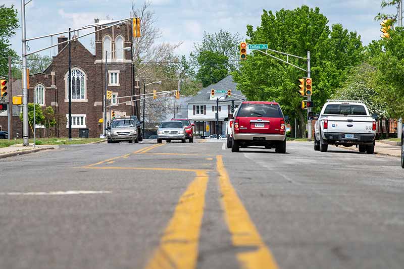 A shot from the middle of a road. Cars wait at a red light.