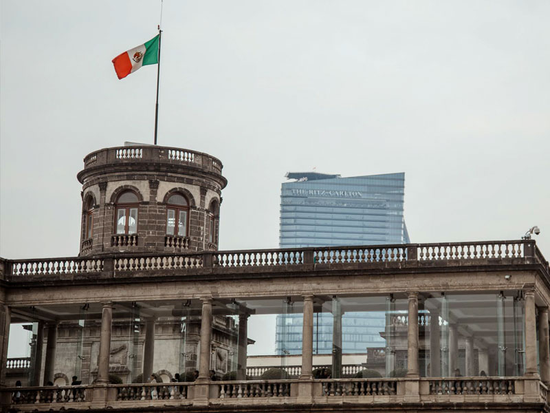 The Mexican flag flies on top of a building.