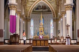 An empty Basilica of the Sacred Heart, a priest is livestreaming a service.
