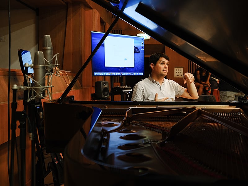 J.J. Wright directing a recording session while seated at a piano