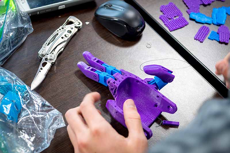 A student cuts and assembles the 3D-printed parts of the prosthetic hands.