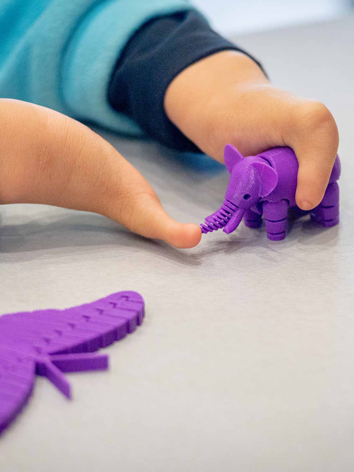 Tori plays with an elephant made on the same 3D printer as her prosthetic hands.