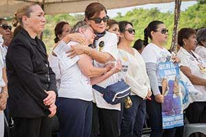 Women listening to the Mass, hugging each other and crying, holding signs with photos of their disappeared children on them.