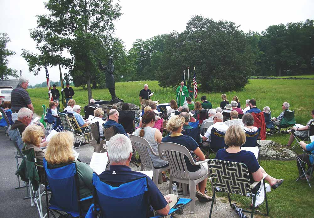 A group of people near the Corby statue at an annual Mass.