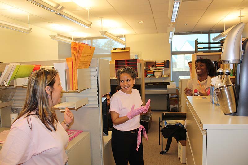 Marie Lynn Miranda in an office with two other women, all wearing pink.