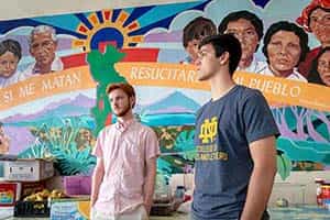 Two Notre Dame students stand in front of a colorful mural