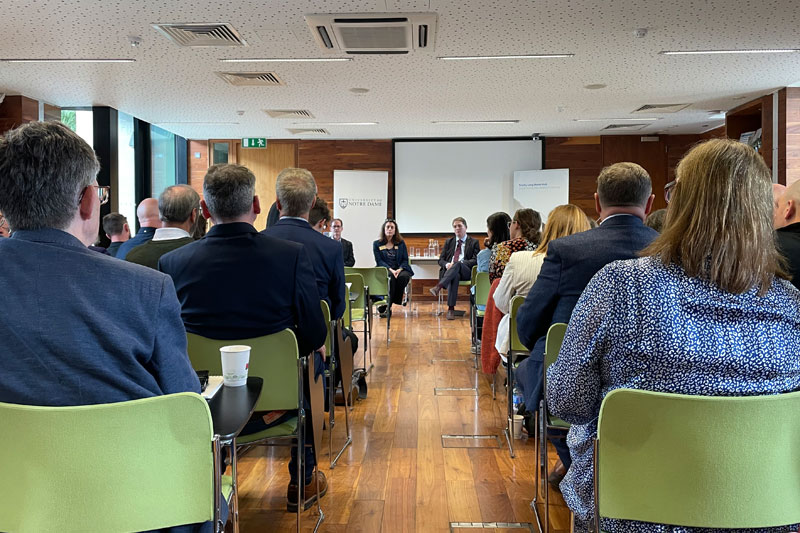 Two sections of people sitting in chairs. There are two people sitting at the front, visible from the aisle.