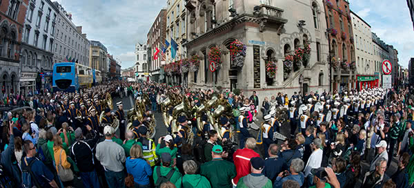 A panoramic view of the marching band walking through the streets of Dublin.