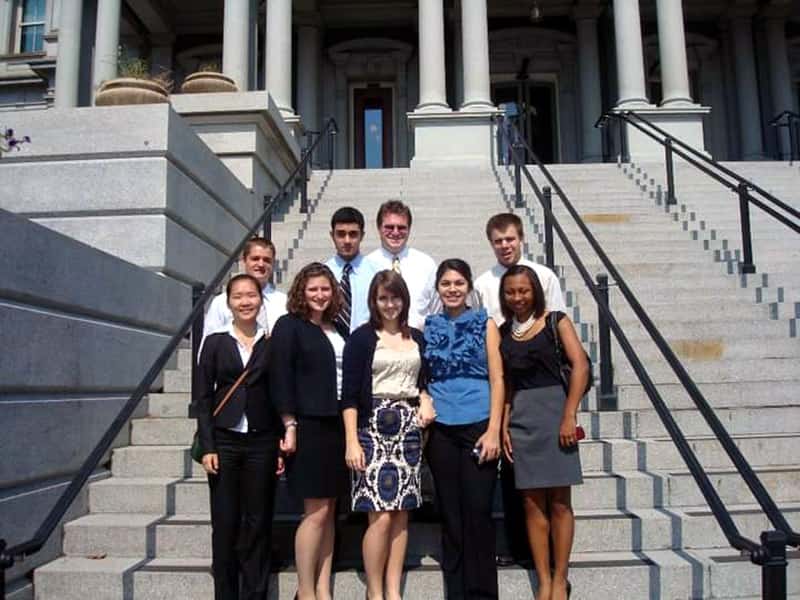 A group of students post for a photo outside on cement stairs.