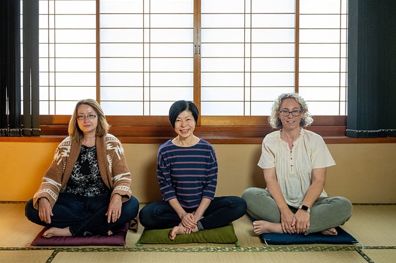 Notre Dame faculty members sit on pillows on the floor. From left to right Anna Geltzer, Noriko Hanabusa, and Jessica McManus Warnell