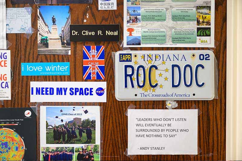 An office door filled with stickers about space, photos, and a license plate that says ROC DOC.