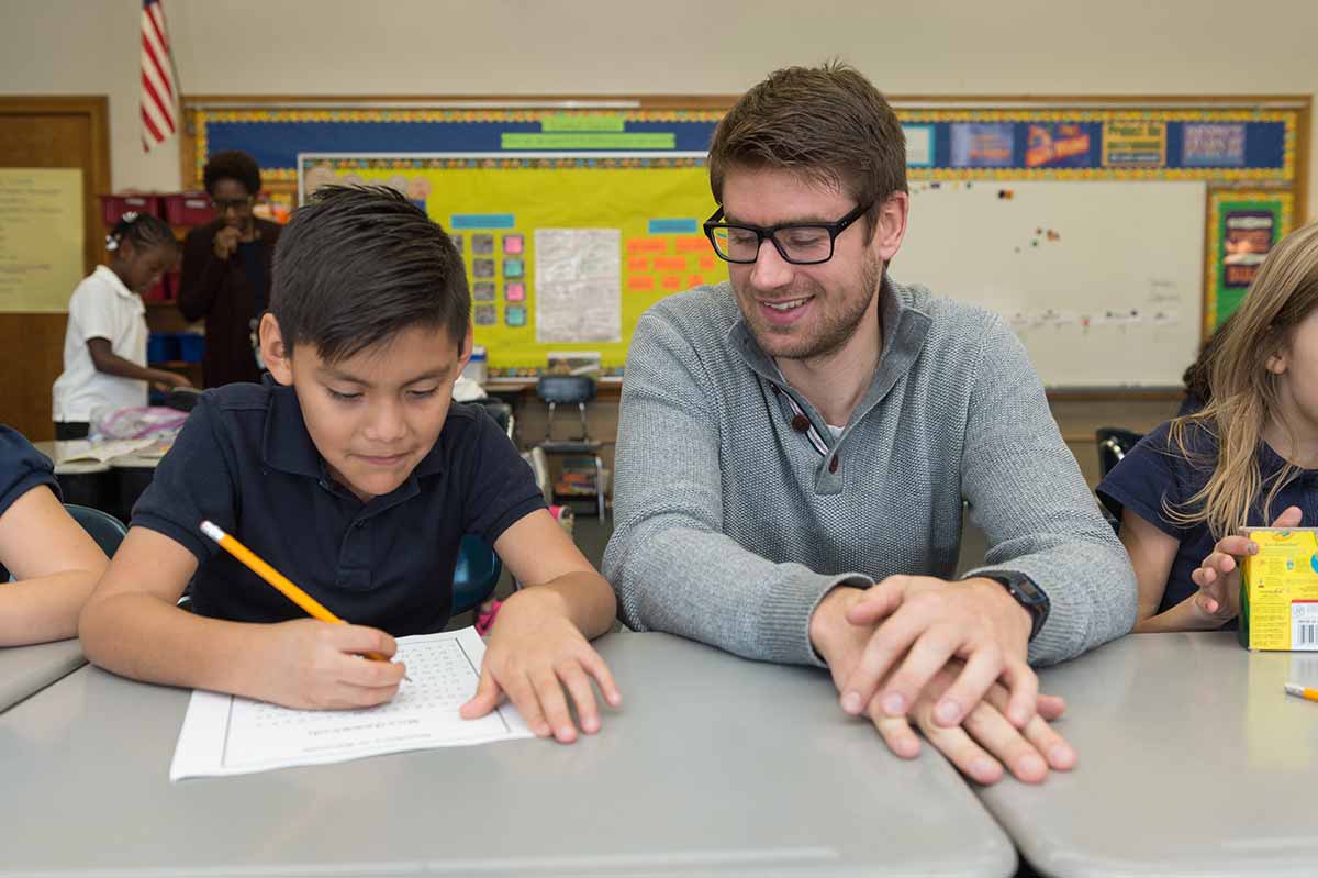 German FLTA Daniel Fastlabend helps a second-grade student with a German word search