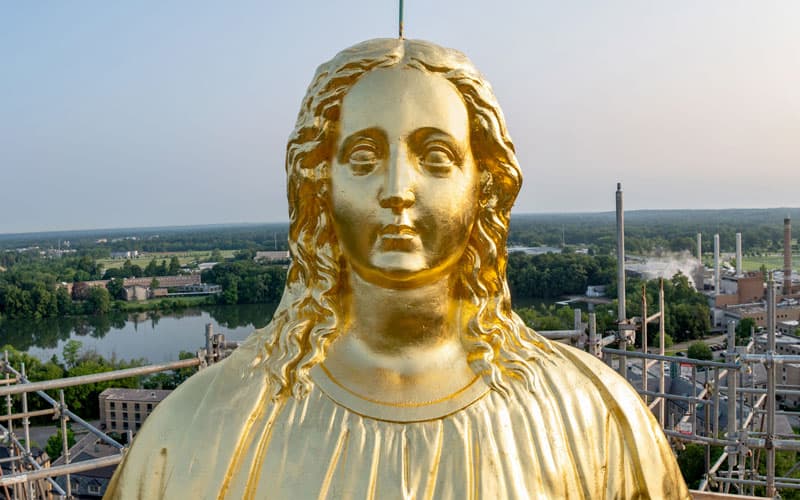 A close up view of Mary's face on the statue on top of the Golden Dome.