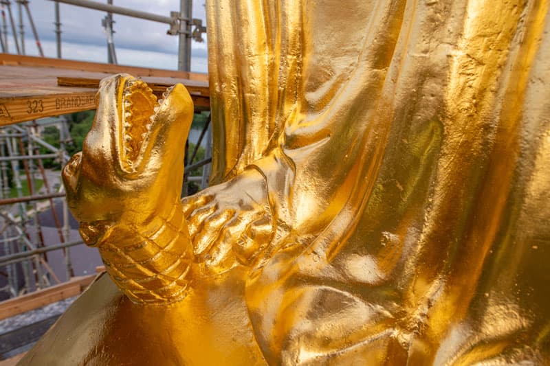 A close up of the serpent at the base of the statue of Mary on top of the Golden Dome.