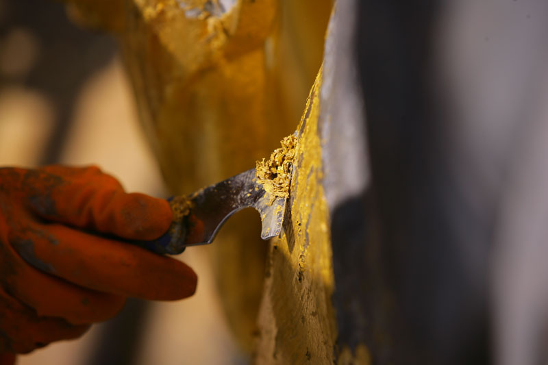 A close up of a scraper removing a layer of gold off the Dome in 2005.
