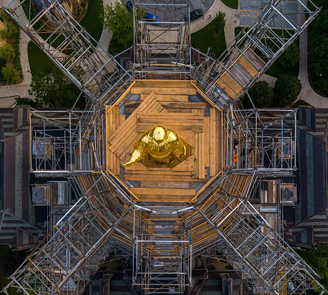 A top view of newly gilded Mary surrounded by scaffolding in a symmetrical pattern.