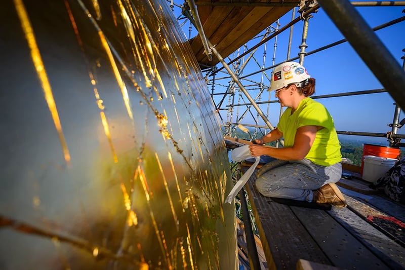 A worker meticulously applies gold leaf to the surface of the Dome.