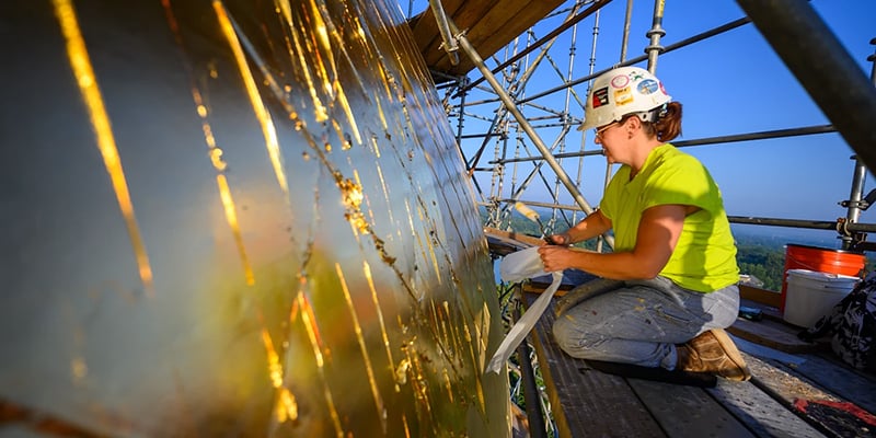 A worker meticulously applies gold leaf to the surface of the Dome.