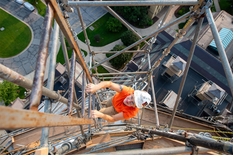 A view from above of a woman climbing scaffolding up to the Golden Dome.
