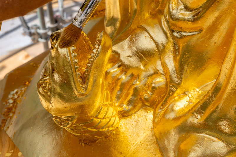 A close of view of the newly gilded snake at the base of the statue of Mary on top of the Golden Dome. The gold is being touched up with a paint brush.