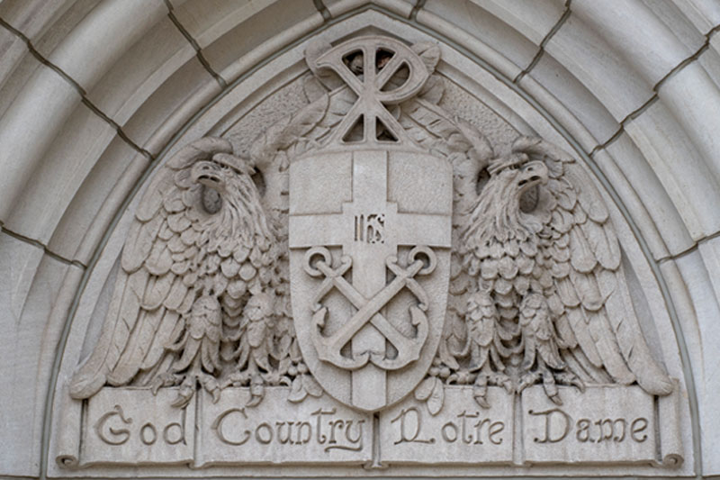 A stone carving that says 'God, Country, Notre Dame on it.