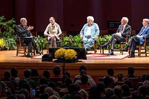 Panelists sit on a stage