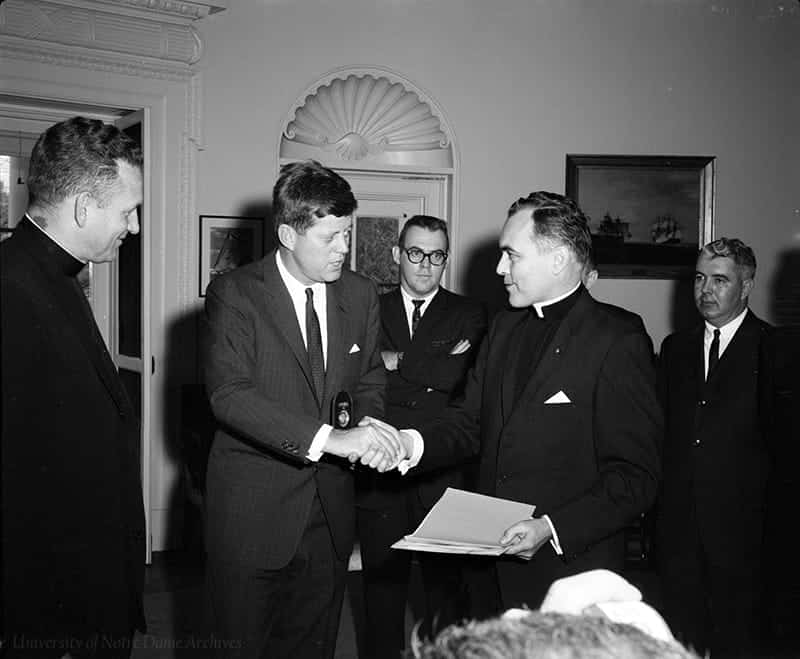 Father Hesburgh shakes Kennedy's hand in the Oval Office.