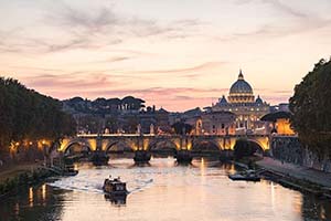 The Vatican and a bridge over a river in Rome at sunset.