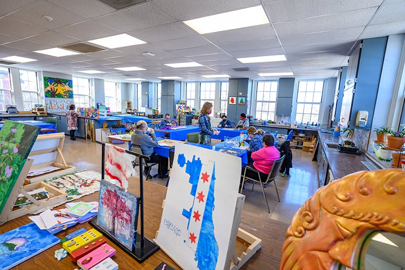 The art studio in Misericordio where people are sitting at tables working on art projects.