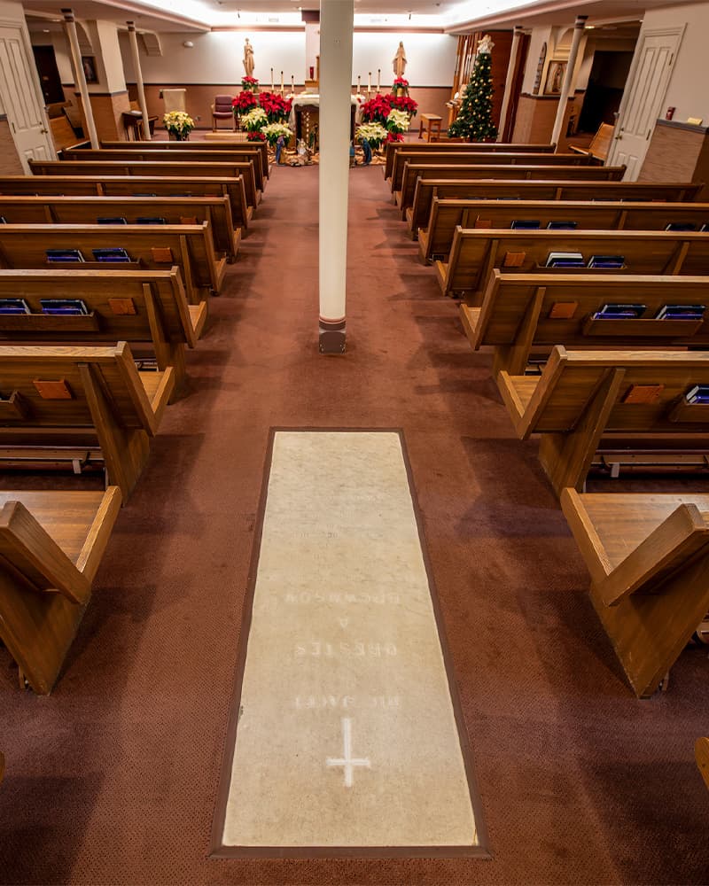 A marble crypt sits between rows of pews in the modest chapel below the Basilica of the Sacred Heart.