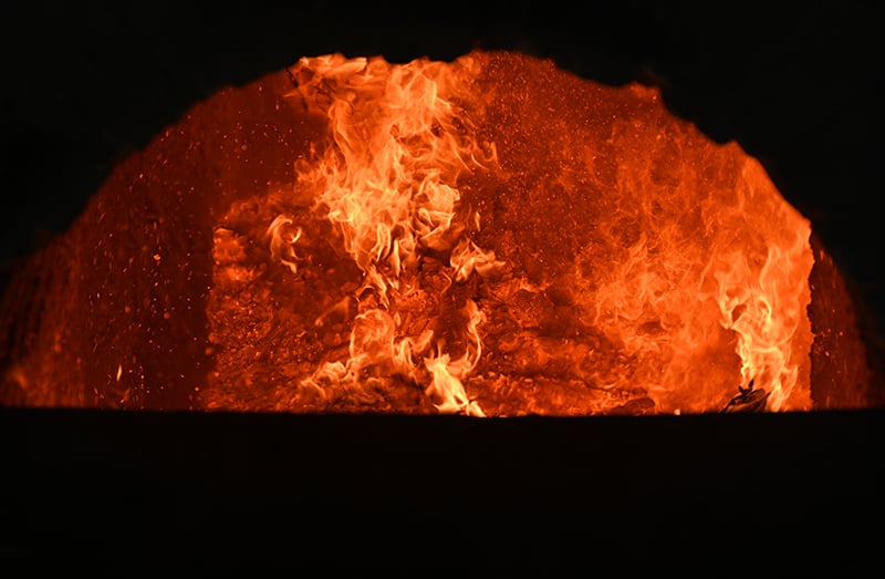 A view inside of the kiln with flames engulfing the entire opening. The foreground is dark.
