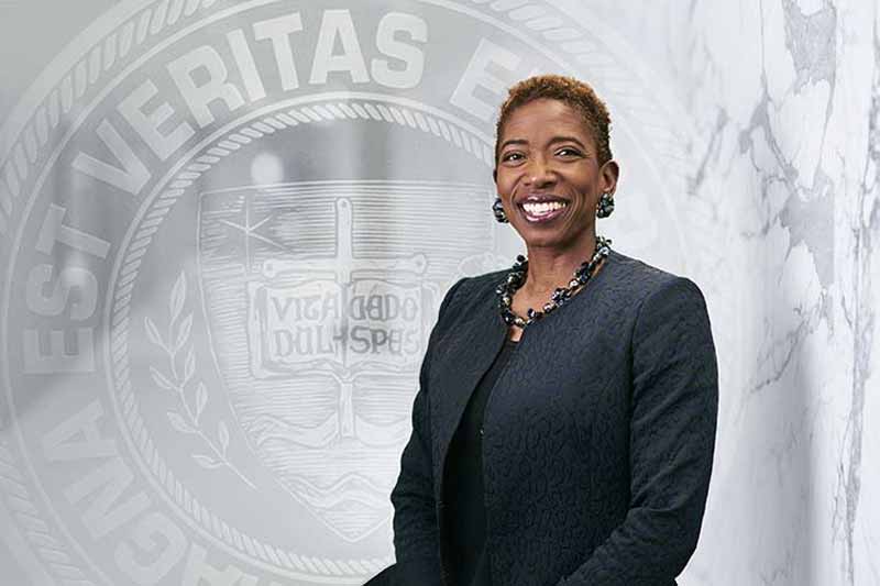 Carla Harris, in front of a background of marble and the Laetare Medal.
