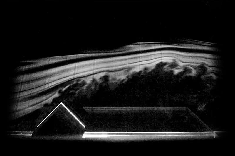 Simulation of airflow around a roof structure in grainy black and white film.
