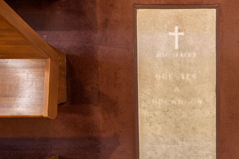 A marble crypt sits between rows of pews in the modest chapel below the Basilica of the Sacred Heart.