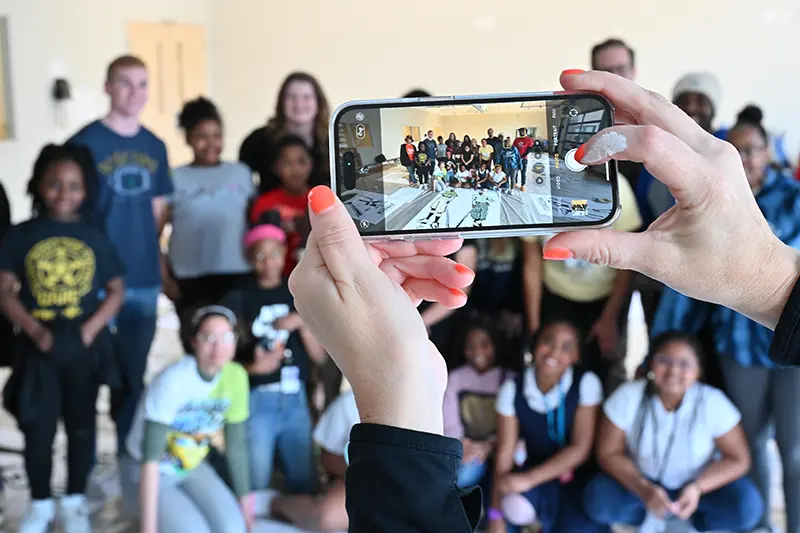 A phone is held up to take a photo of the team after working to paint murals.