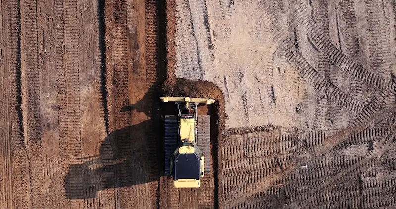 A bulldozer clearing dirt on a ball field.