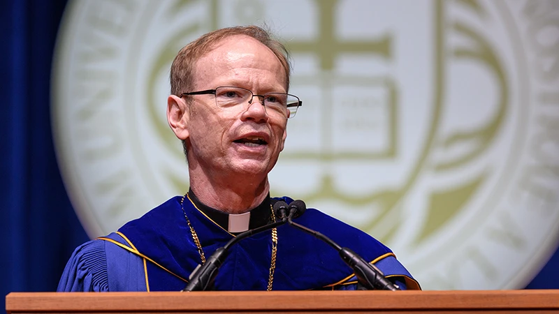 Fr. Dowd giving a speech at a podium during Inauguration ceremonies.