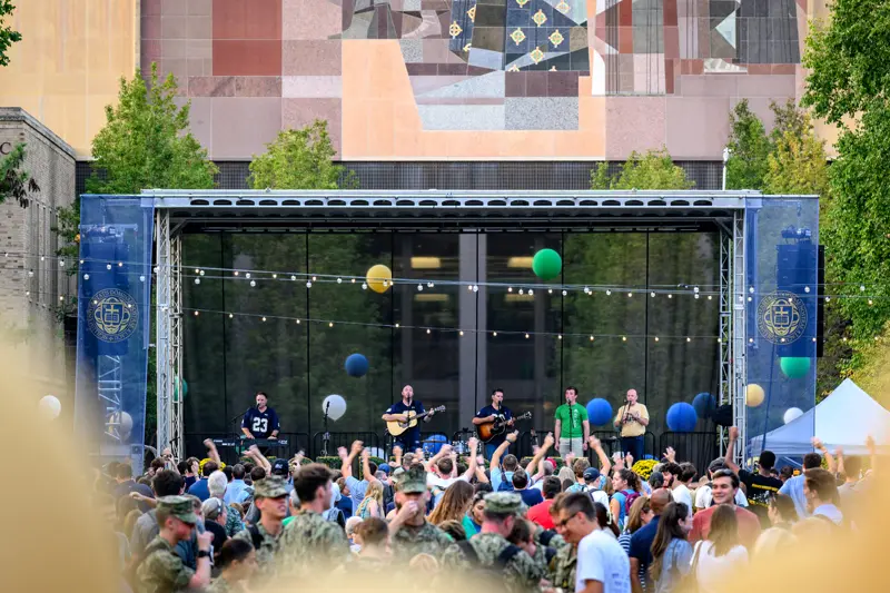 The Irish band The High Kings stand on stage performing for a crowd in front of the Hesburgh Library.